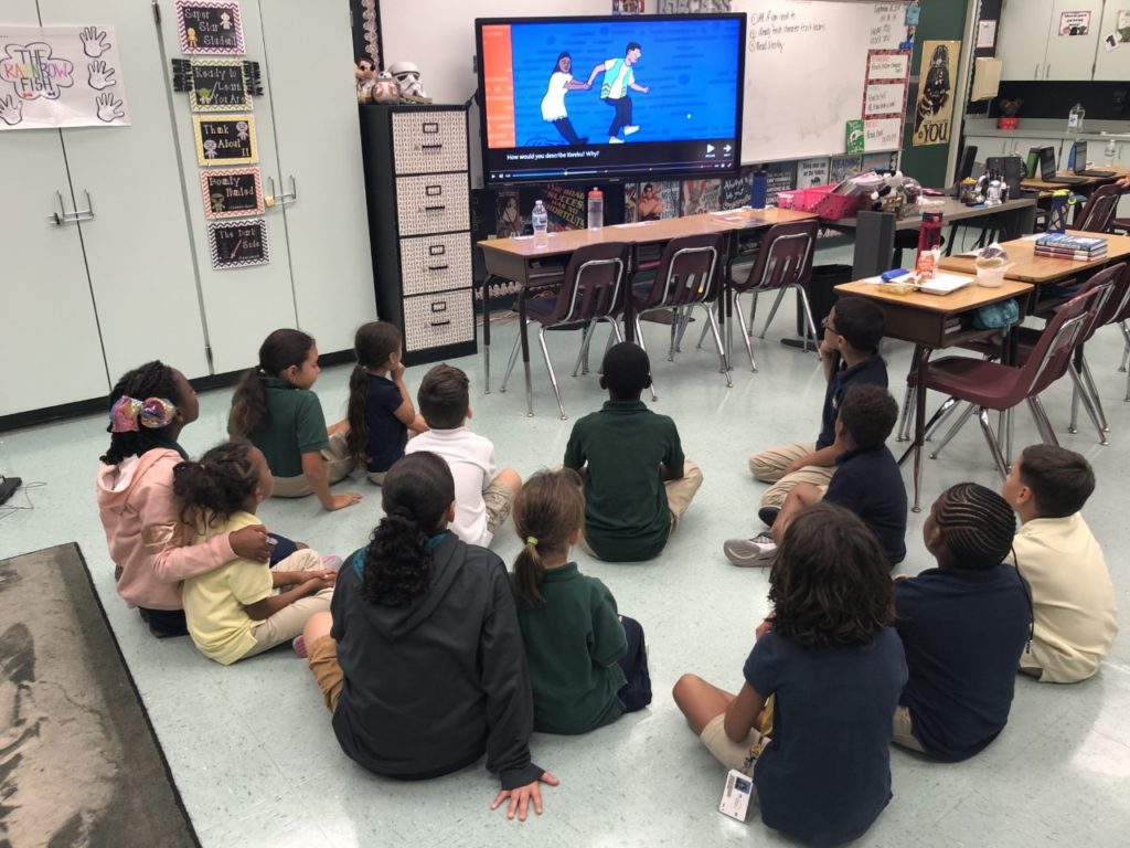 Üçüncü sınıf öğrencileri ve anaokulu öğrencileri, küçük grup eğitiminin bir parçası olarak Flocabulary şarkı sözlerini anlamak ve kelime öğrenmek için arkadaş olurlar