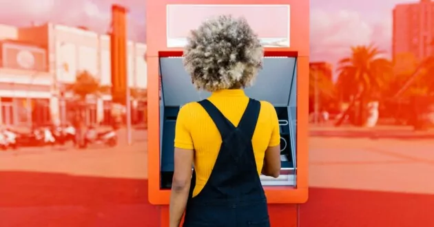 작업복을 입고 빨간색 ATM 기계를 사용하는 사람