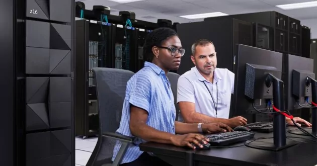 Team of two engineers working on computer in server room with IBM z16