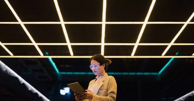 Junger Geschäftsmann trägt nachts eine Augmented-Reality-Brille und nutzt ein Tablet