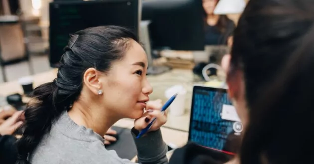 Góc nhìn cao của đồng nghiệp nữ đang thảo luận qua máy tính xách tay khi ngồi ở bàn làm việc trong văn phòng
