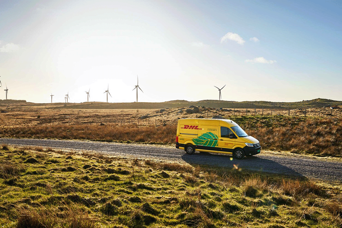 業界の二酸化炭素排出量_DHL 配送トラック、背景の風力タービン_ビジュアル 3