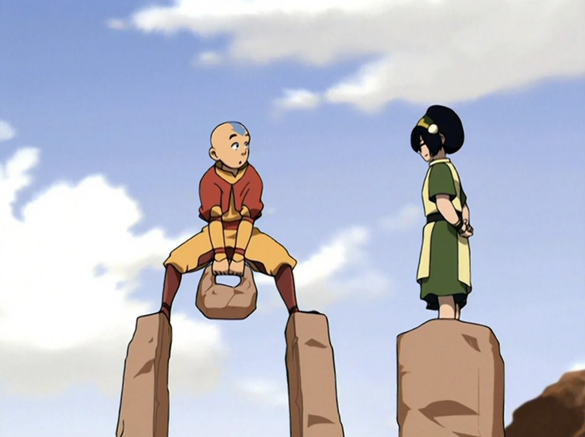 Aang de pie y sosteniendo una roca sobre dos pedestales mientras Toph está de pie sobre uno instruyéndolo.