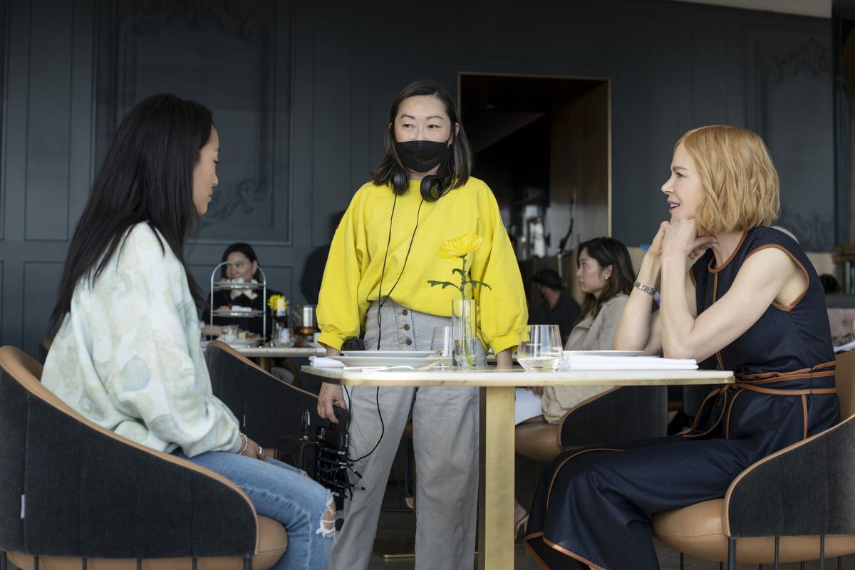 Lulu Wang standing at a table with Ji-young Yoo and Nicole Kidman behind the scenes of Expats