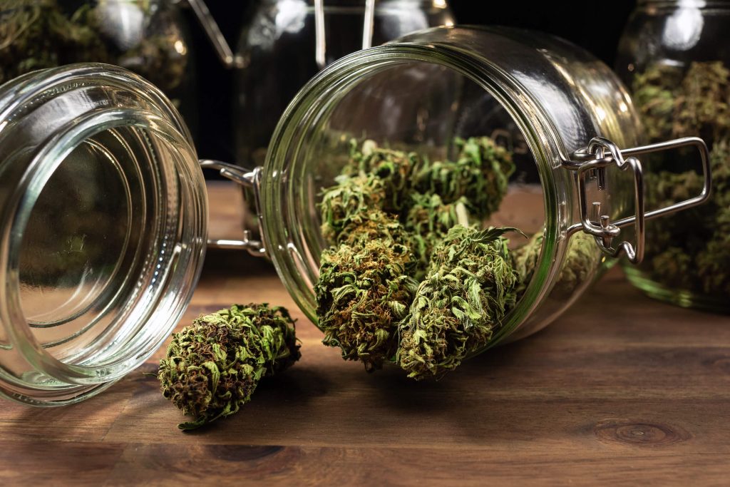 Gedroogde cannabisbloemen die uit de glazen pot vielen