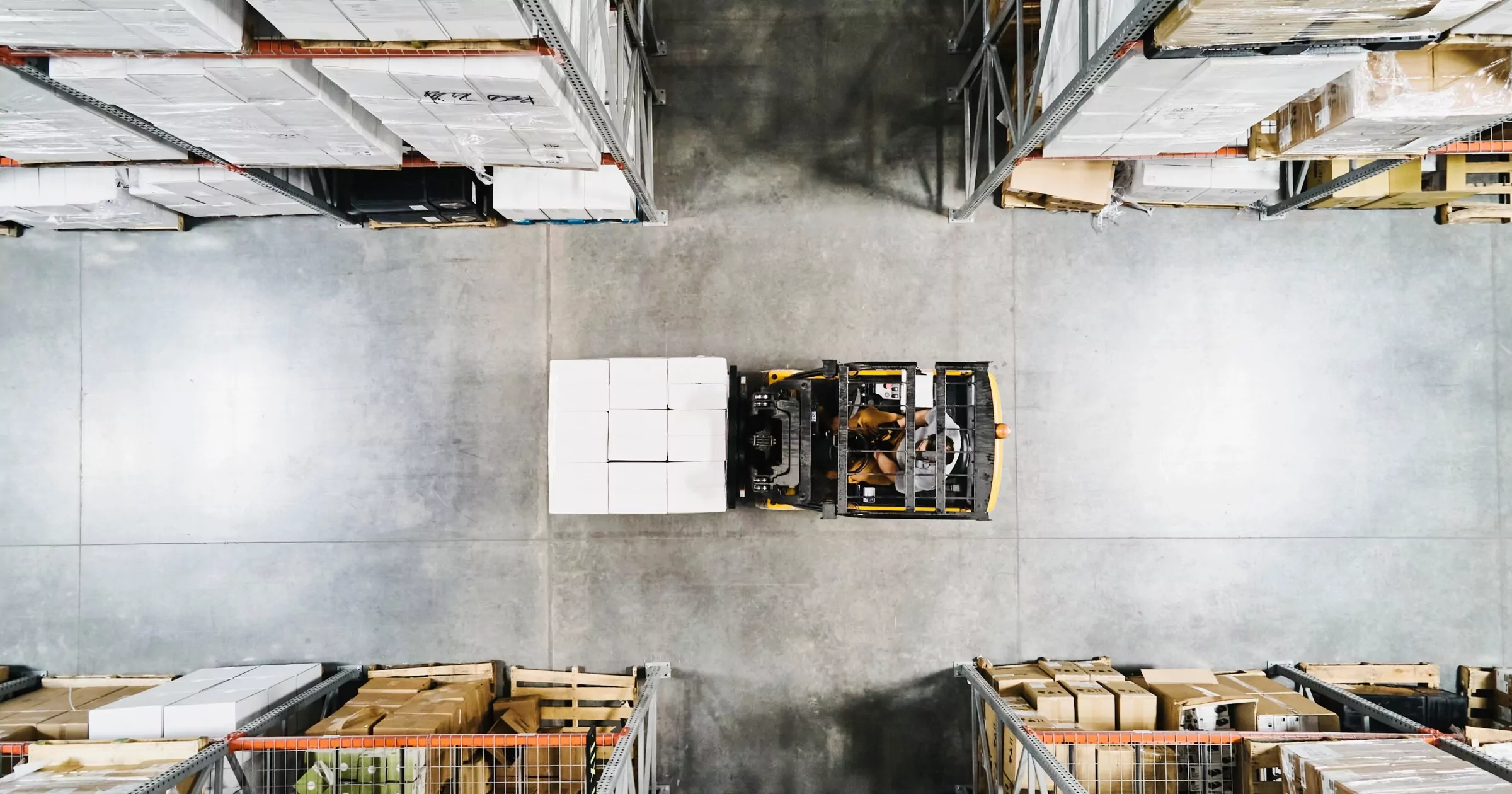 Vue aérienne d'un employé d'entrepôt déplaçant une palette de marchandises avec un chariot élévateur dans un entrepôt