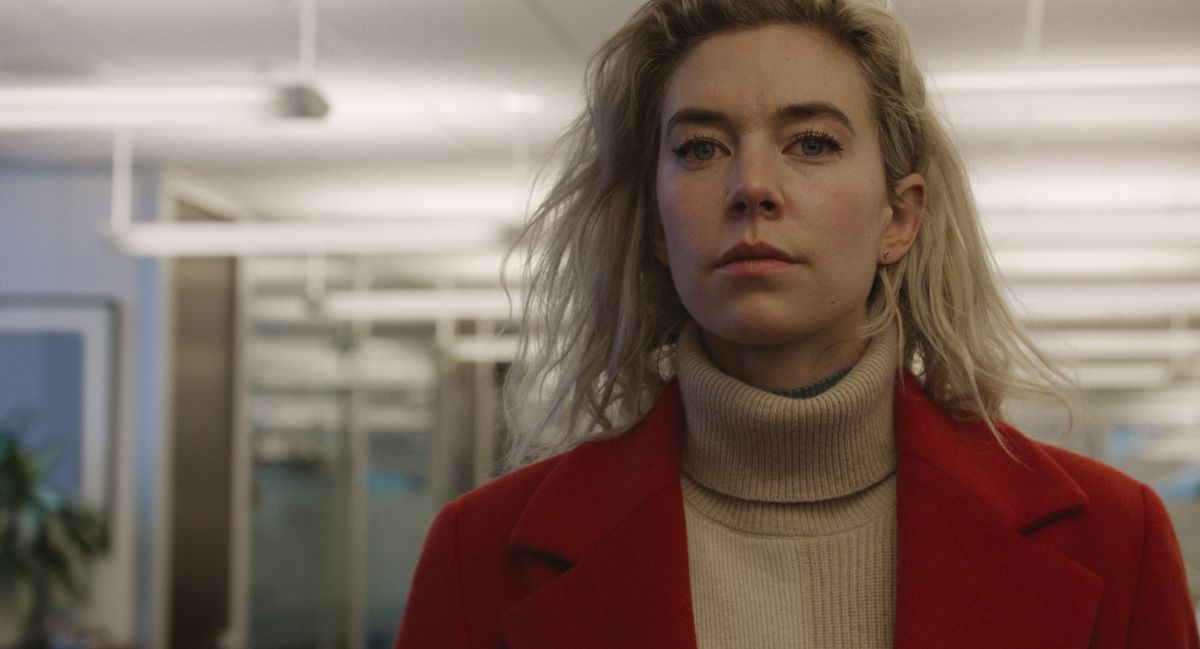 Vanessa Kirby loopt in een rode jas en warrig haar door een kantoorgebouw in Pieces of a Woman