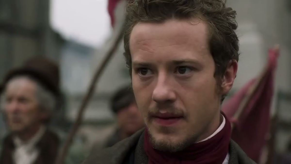A close up of Joseph Quinn as Enjolras, looking determined