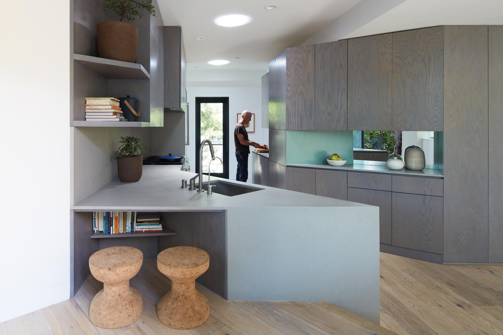 The cabinets in the kitchen are painted a gray tone that echoes the olive tree outside.