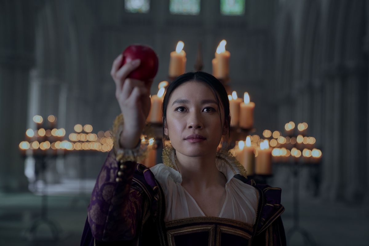 Jin Cheng (Jess Hong) giơ một quả táo trong hội trường thời trung cổ trong 3 Body problem.