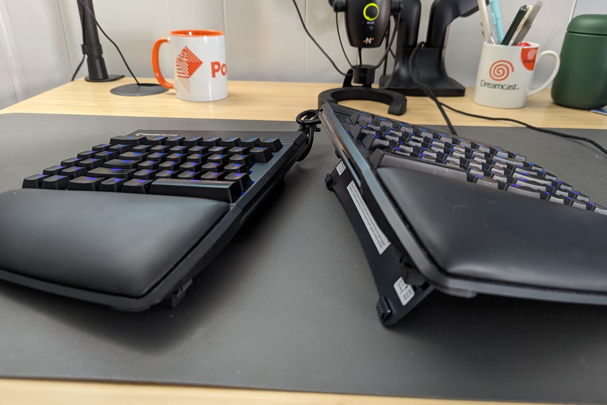 Een afbeelding van het Kinesis FreeStyle Edge RGB ergonomisch gesplitst toetsenbord op een bureau. De Lift-kit is aan elke toetsenbordhelft bevestigd en de helften zijn onder verschillende hoeken gekanteld om de functies ervan te illustreren.