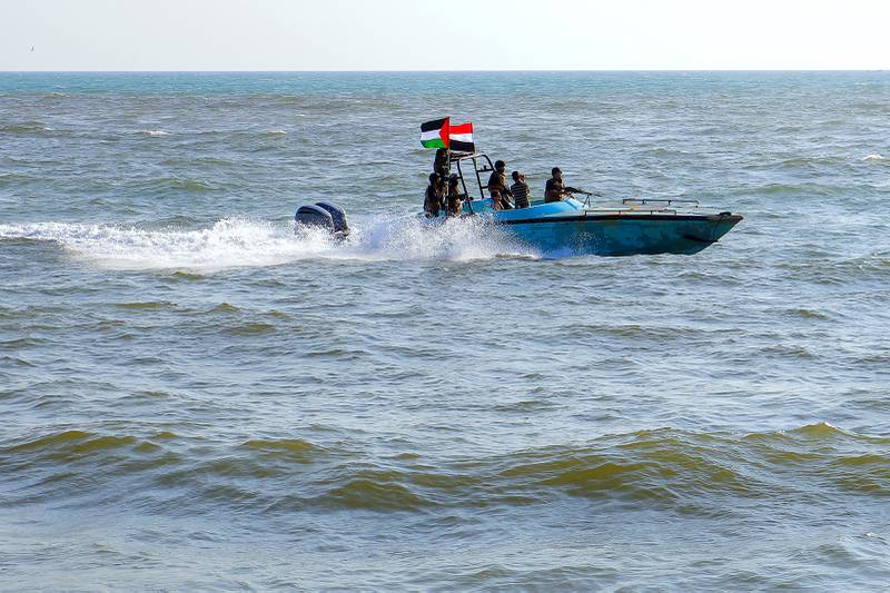 Leden van de Jemenitische kustwacht, aangesloten bij de Houthi-groep, patrouilleren op zee terwijl demonstranten op 4 januari 2024 door de havenstad Hodeida aan de Rode Zee marcheren.