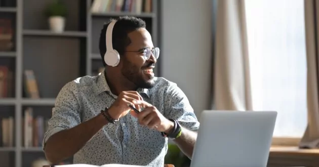 Persona de negocios sentada frente a una computadora portátil, mirando hacia un lado y sonriendo