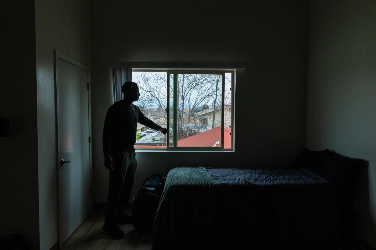 Un joven abre la ventana de un apartamento ordenado.