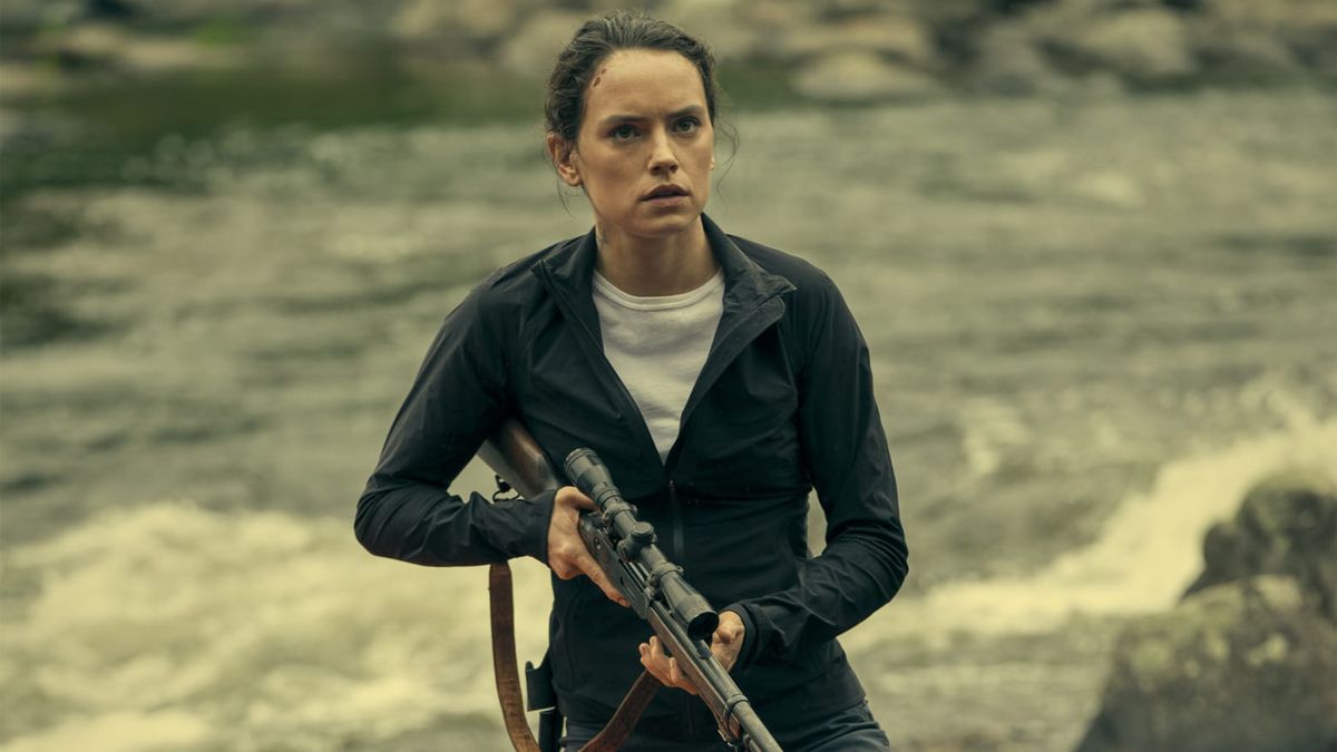 Daisy Ridley hält ein Gewehr in der Hand, während sie in „The Marsh King's Daughter“ vor einem Fluss steht.