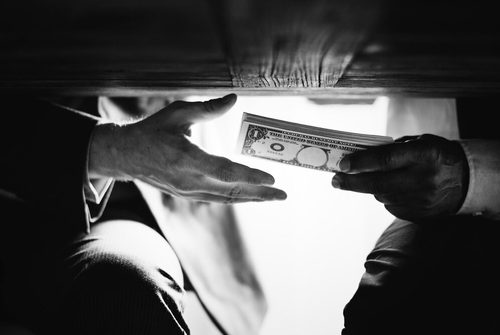 an image of a person bribing another, under the table. 