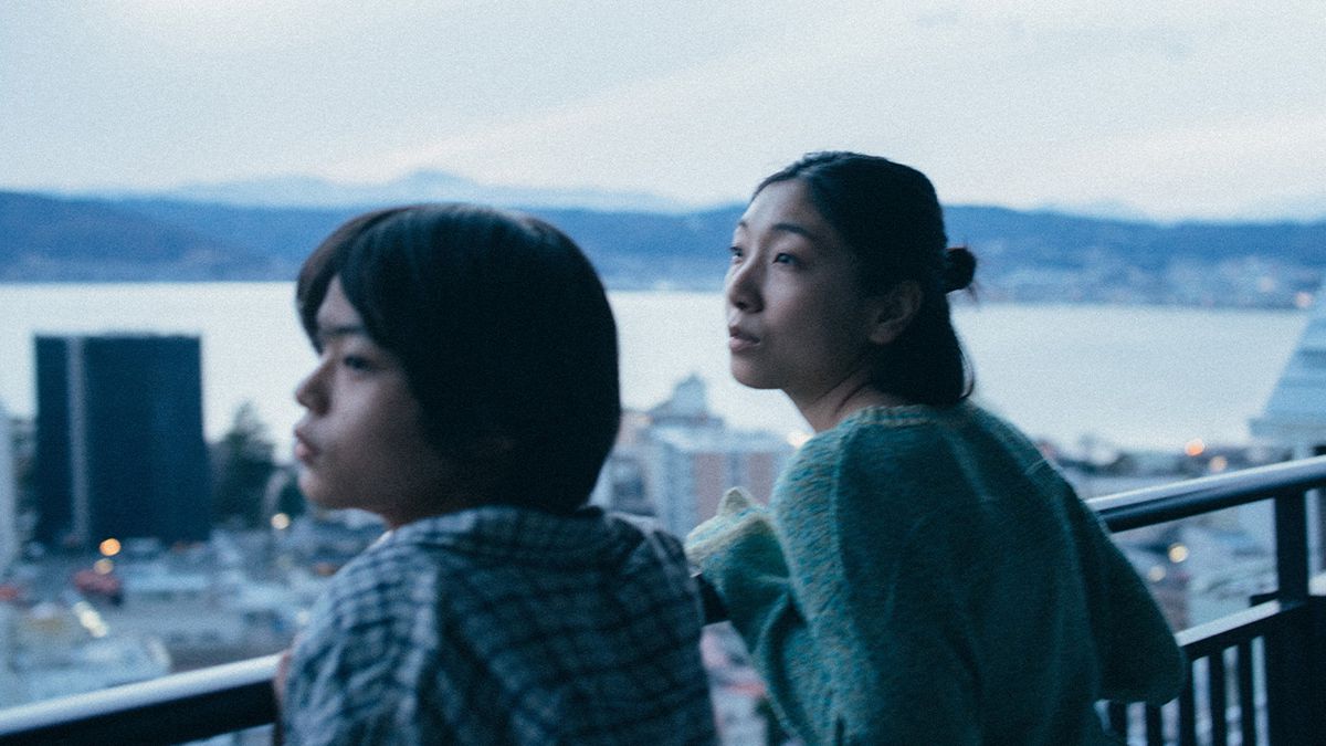 Sakura Andō y Sōya Kurokawa se apoyan en una barandilla sobre un paisaje urbano en Monster