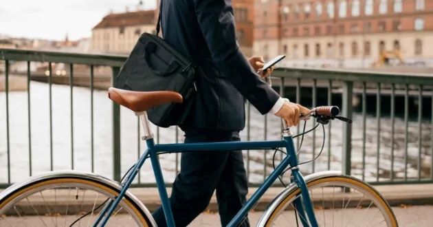 Man loopt met de fiets terwijl hij aan de telefoon is.