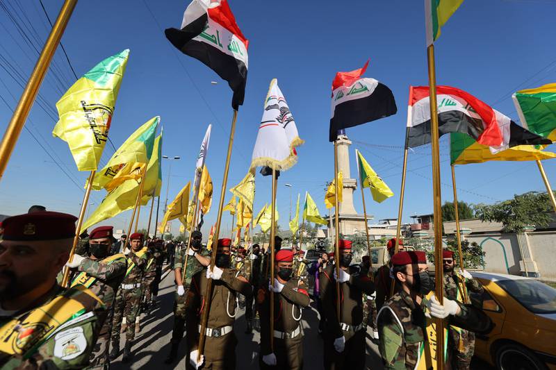Los combatientes levantan banderas de Irak y de grupos paramilitares, incluidos al-Nujaba y Kataib Hezbollah, durante un funeral en Bagdad, Irak, tras un ataque estadounidense.