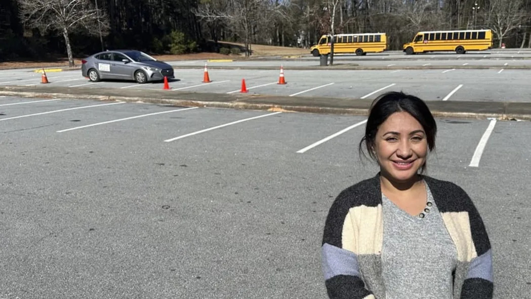 Η Nancy Gobran, ιδιοκτήτρια και εκπαιδεύτρια του Safety Driving School στέκεται χαμογελώντας μπροστά σε έναν οδηγό