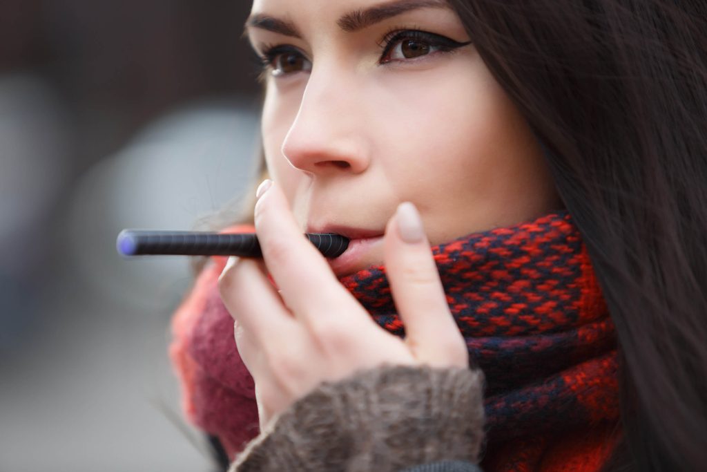 Chica de pelo castaño con pañuelo rojo fumando un bolígrafo negro