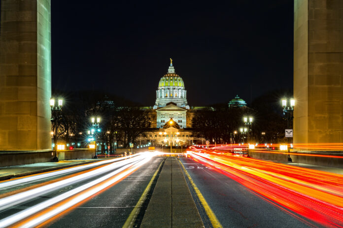 Pennsylvania state capitol at night with car lights streaking through with open camera shutter
