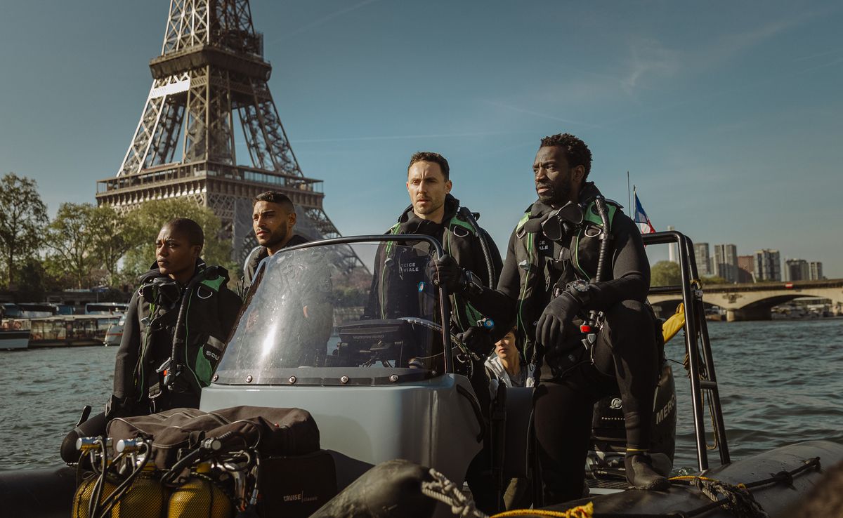 A group of River Brigade police ride a launch down the Seine river in front of the Eiffel Tower in Xavier Gens’ Netflix shark thriller Under Paris