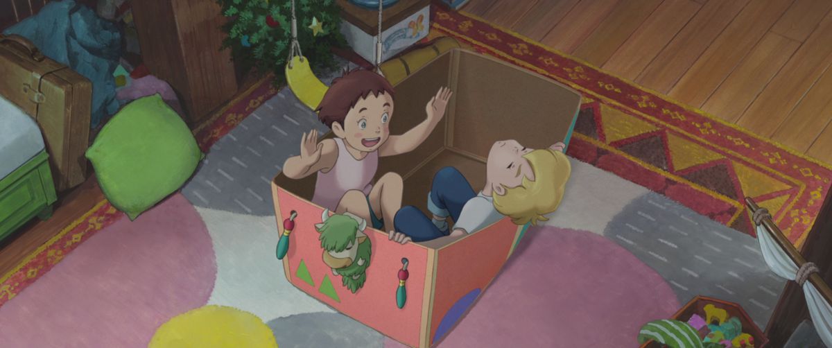 Young girl Amanda gesticulates enthusiastically as her imaginary friend Rudger slumps back against the side of the pink, decorated cardboard box they’re both sitting in, in a scene from Studio Ponoc’s anime movie The Imaginary 