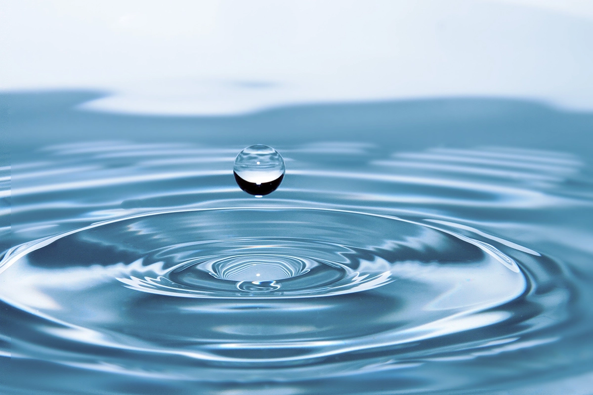 A water droplet above a rippling pool