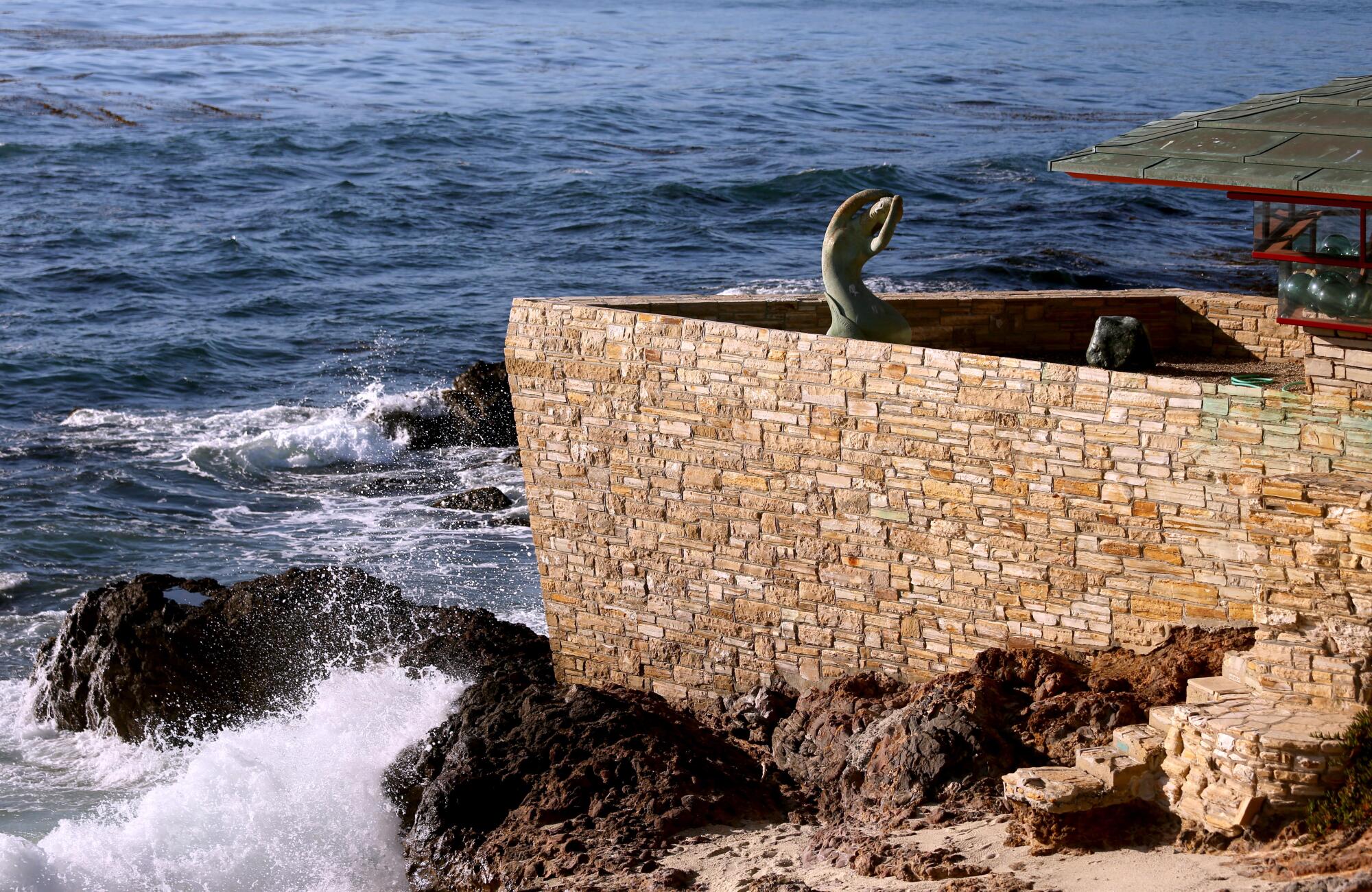 The stone walls of an historic home jut into the ocean like the prow of a ship. 