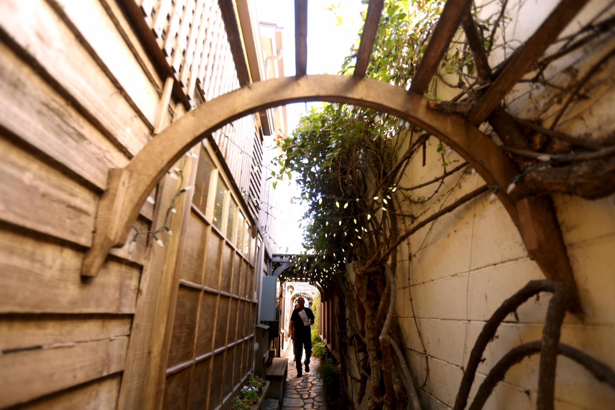 A visitor makes his way through a narrow outdoor passageway.