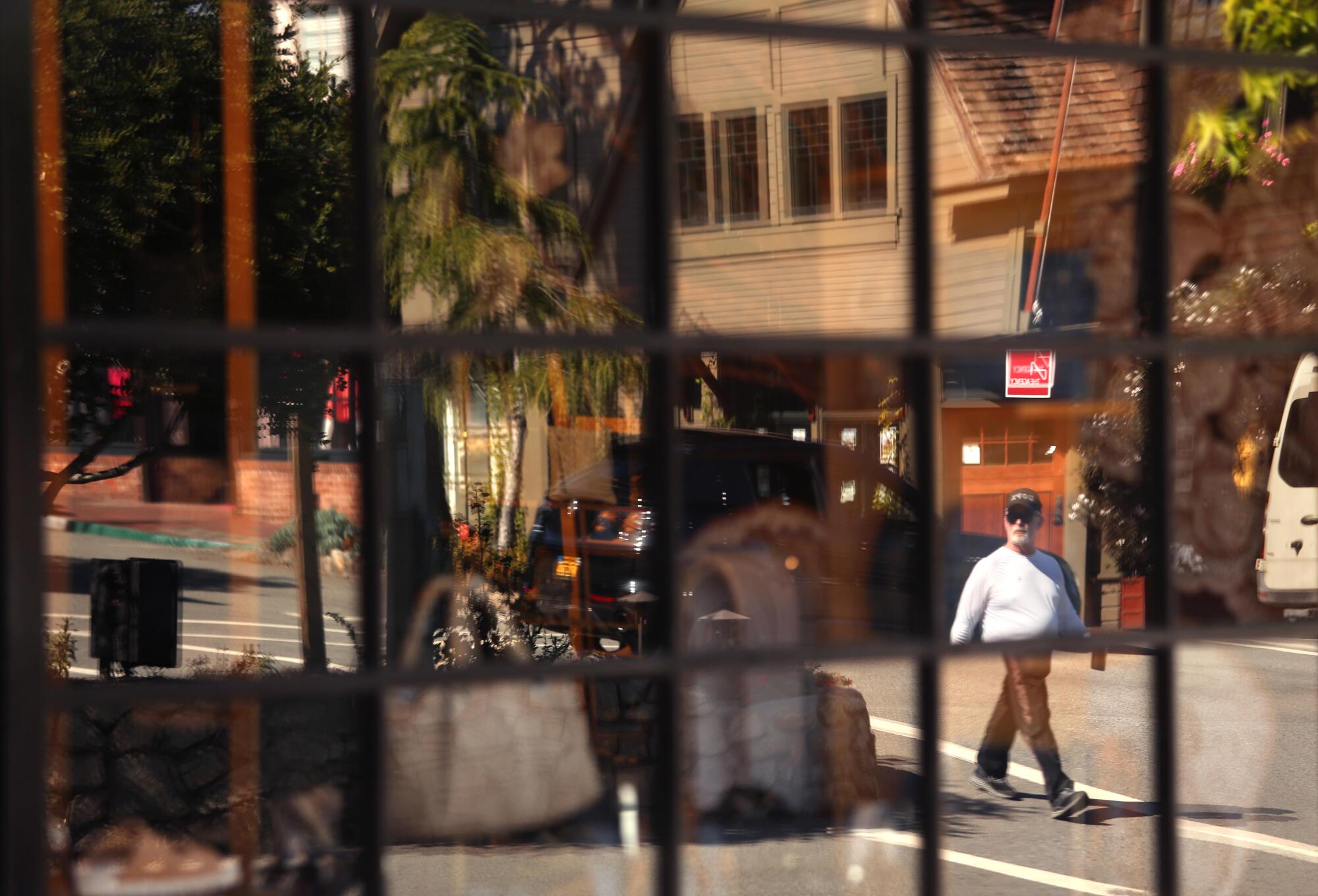 A pedestrian is caught in a reflection of a storefront window.